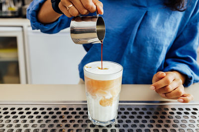 Midsection of man pouring coffee in cup