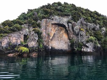 Rock formation by lake against sky