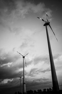 Low angle view of silhouette windmills against sky