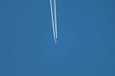 Low angle view of airplane flying against clear blue sky