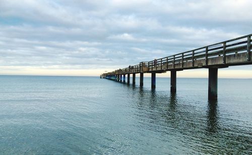 Pier over sea against cloudy sky