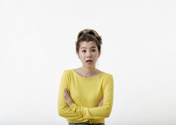 Portrait of young woman standing against white background