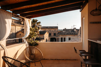 Spacious terrace with rattan chairs and stool placed at bar counter in scenic town with aged residential buildings on sunny day in mallorca