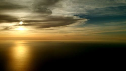 Scenic view of sea against cloudy sky at sunset