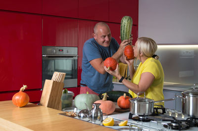 Mature couple holding vegetables in kitchen
