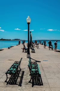 People on pier against blue sky