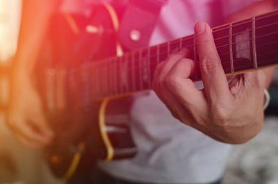Midsection of man playing guitar