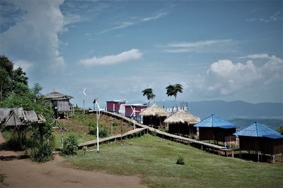 Houses on field by buildings against sky