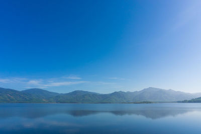 Scenic view of lake and mountains against blue sky