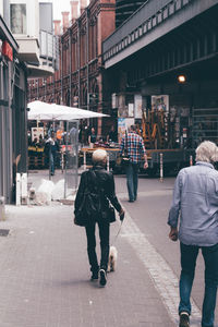 Rear view of people walking on street in city