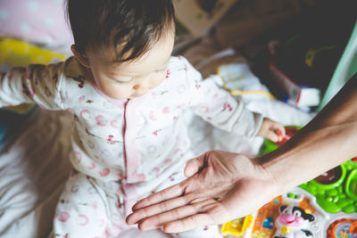 Cropped hand of woman holding insect with daughter at home