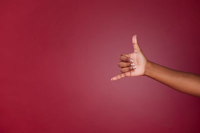 Cropped hand of woman gesturing against blue background