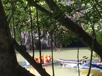 People sitting on boat against trees