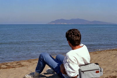 Rear view of man sitting on beach