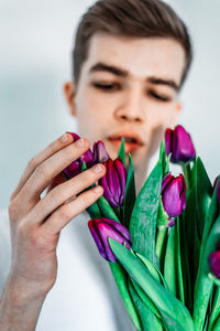 Close-up of woman holding bouquet against blue background