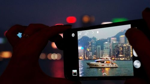 Person holding mobile phone against buildings in city