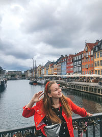 Woman with umbrella against sky in city