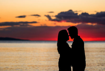 Silhouette woman standing at beach against sky during sunset