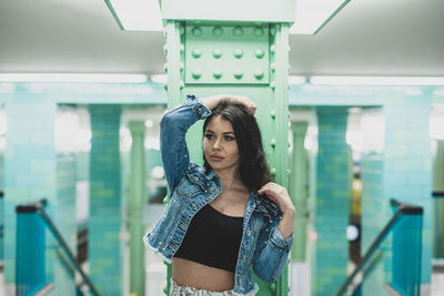 Portrait of young woman standing against blurred background