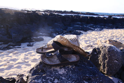 Close-up of rusty metal on rock at beach against sky