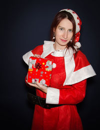 Portrait of smiling woman in santa claus costume against black background