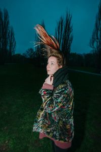 Woman looking away while standing on grass against sky