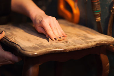 Close-up of woman sanding furniture with sand paper