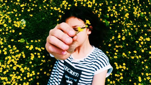 Directly above shot of woman holding flower while lying on grass at park