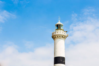 Low angle view of lighthouse by building against sky