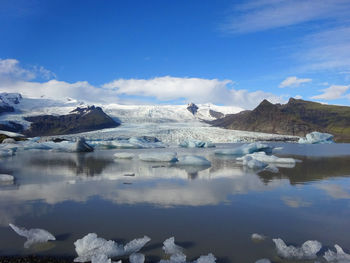 Scenic view of lake and snowcapped mountains against sky