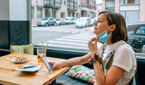 Young woman using phone while sitting on table