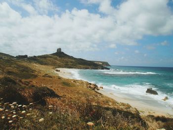 Scenic view of beach against cloudy sky