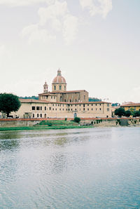 Buildings by river against sky