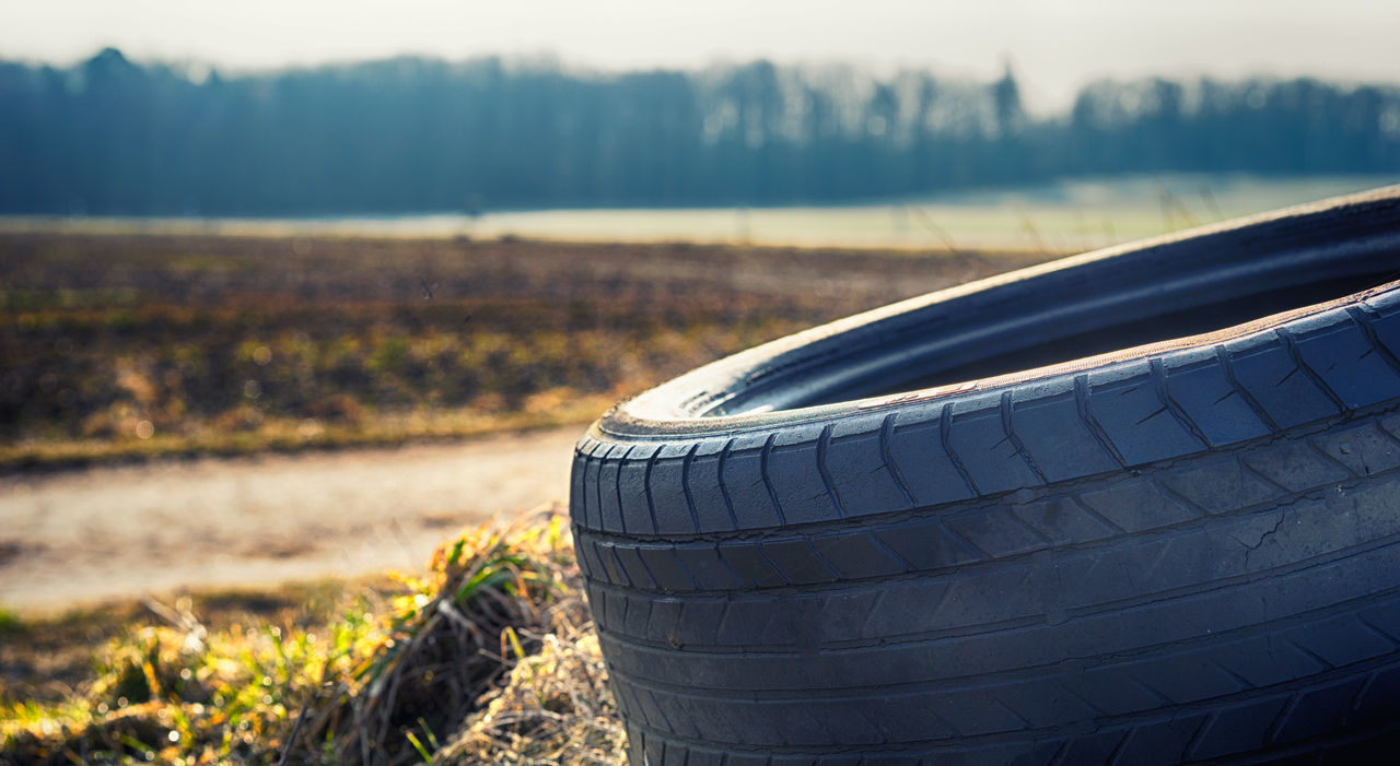 CLOSE-UP OF BLACK TIRE ON FIELD