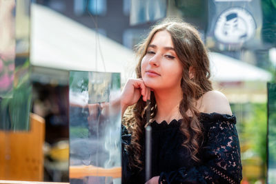 Portrait of smiling young woman sitting at sidewalk cafe