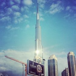 Low angle view of skyscrapers against cloudy sky