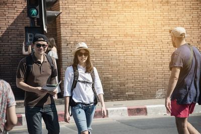 Portrait of couple walking on road against wall