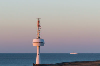 Lighthouse by sea against clear sky