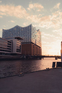 River by buildings against sky during sunset in city