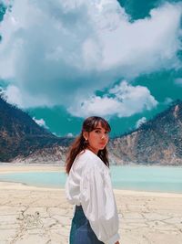 Young woman standing at beach against sky