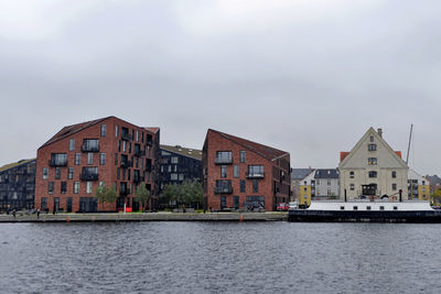 Buildings by river against sky