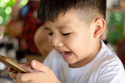 Close-up portrait of cute boy holding camera