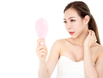 Portrait of woman holding ice cream against white background