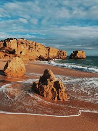 Rock formations on beach against sky