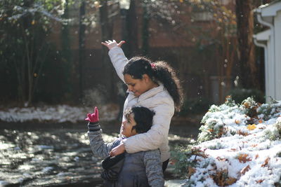 Mother embracing son while standing on footpath during winter