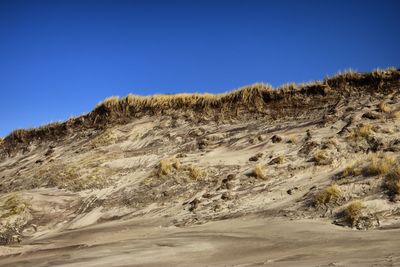 Scenic view of arid landscape against clear blue sky