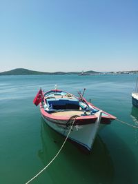 Boat moored in sea against clear blue sky