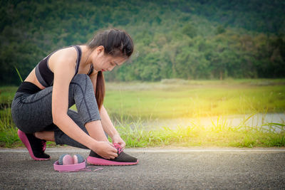 Full length of woman tying shoelace