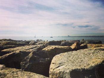 Rocks at sea shore against sky