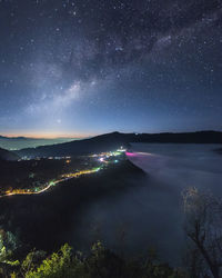 Scenic view of illuminate town by sea against sky at night